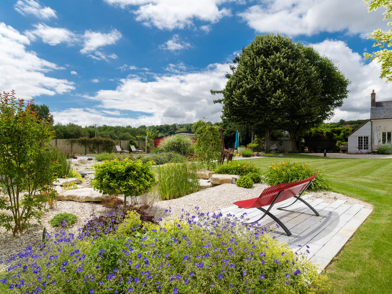 jardin et bassin avec banc fermob coloris coquelicot et terrasse en dallage