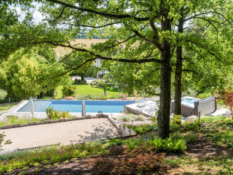 massif de sous bois avec piscine paysagée en second plan