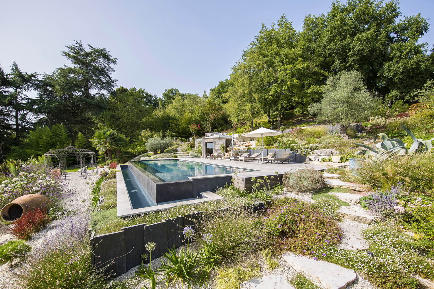 piscine à débordement paysagée avec marche en pierre et terrasse bois