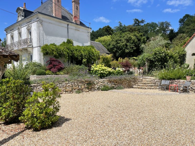 Jardin en terrasses avec murets en pierre, cour gravillonnée et maison de maitre