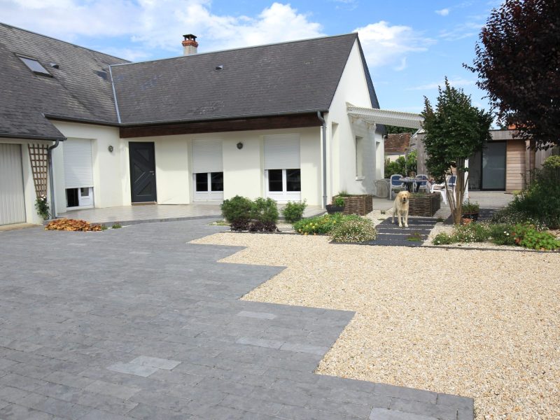 Maison moderne avec cour mixte pavés et graviers, massifs paysagers et pergola